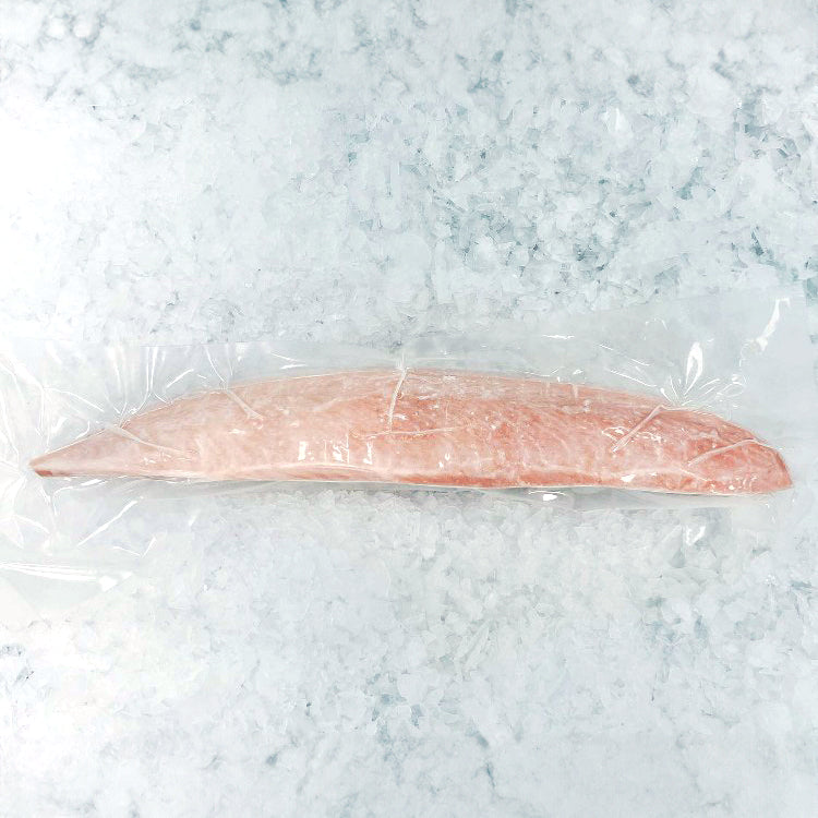 Frozen albacore tuna loin vacuum-sealed in clear plastic packaging on a bed of ice
