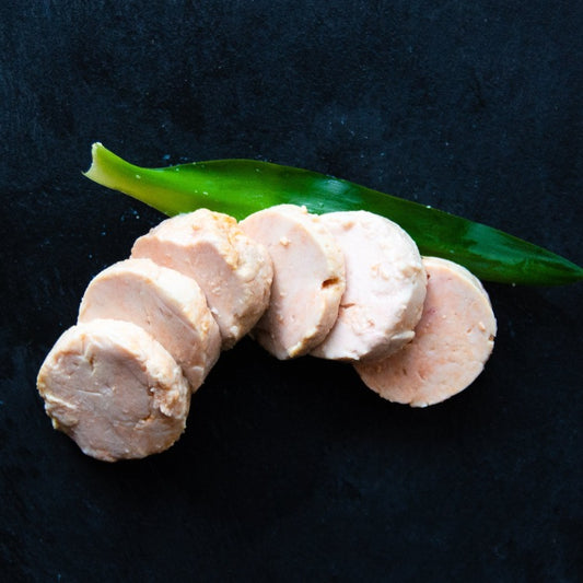 Sliced Monkfish liver on a dark surface garnished with a green leaf
