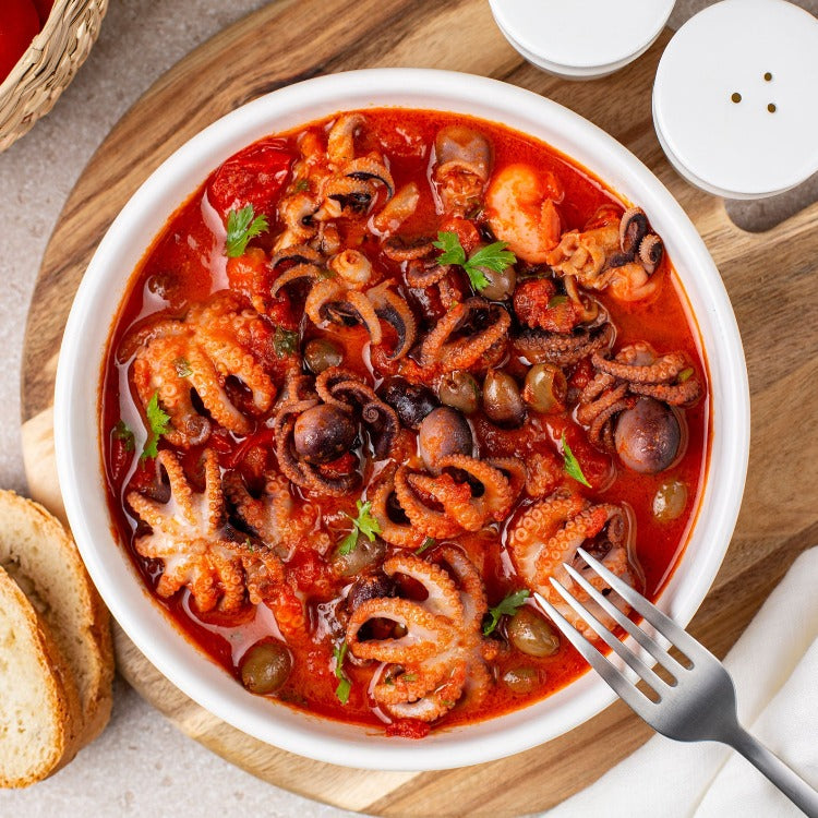 Hearty and spicy baby octopus stew in a white bowl, garnished with herbs, showcasing a traditional seafood dish perfect for a warming meal