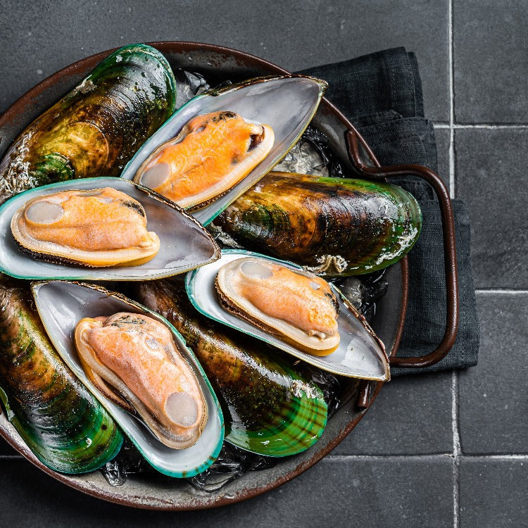 Half-shell mussels cooked and served in a rustic metal pan, emphasizing their appetizing color and ready-to-eat appeal, ideal for a seafood feast