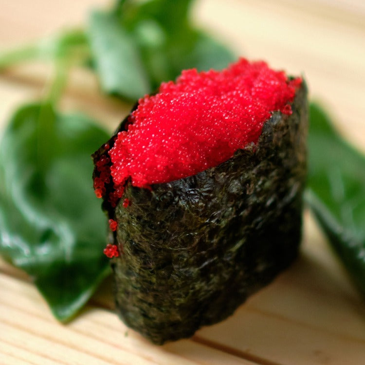 Gunkan maki sushi with a generous topping of Habanero Capelin Roe on a wooden surface