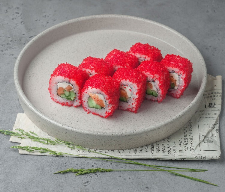 Sushi rolls topped with vibrant red Habanero Capelin Roe on a grey plate