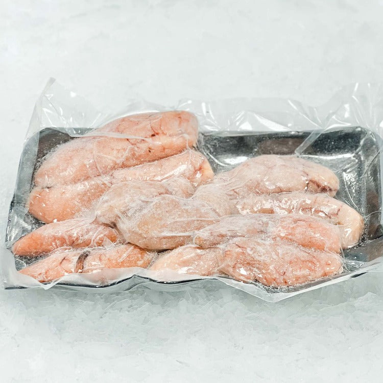 This image displays a package of frozen pollock roe, contained in a clear plastic wrap over a styrofoam tray. The roe appears slightly pinkish in color, each piece individually frozen and visible through the frost-covered plastic, set against a background of crushed ice to emphasize freshness