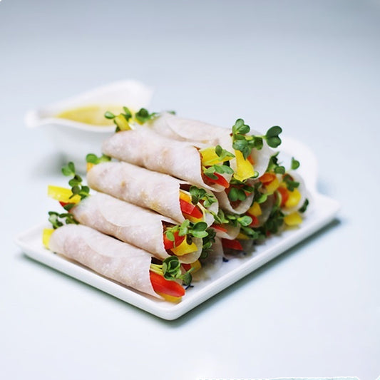 Rolled vegetables with kaiware radish sprouts, presented on a white plate