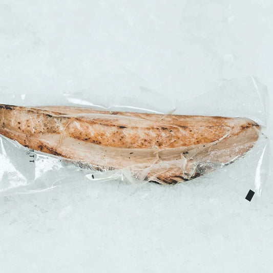 Packaged grilled skipjack tuna (Katsuo tataki) fillet, vacuum-sealed and placed on ice. The fillet is partially cooked with grill marks, showcasing its quality and freshness
