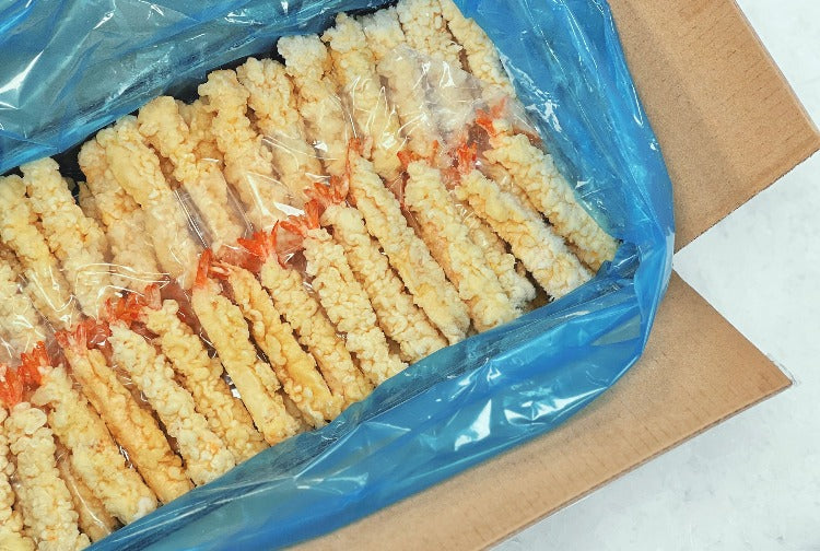 Large pack of breaded tempura shrimp, arranged in a blue plastic-lined box, viewed from a different angle