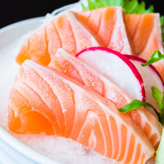 Close-up of fresh salmon sashimi slices garnished with radish and greens. Perfect for sushi and sashimi lovers, highlighting the rich, vibrant color and marbling of the salmon