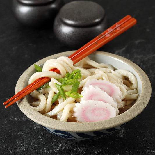 Narutomaki Fish Cake Slices in Udon Soup - Traditional Japanese Dish with Green Onions and Chopsticks