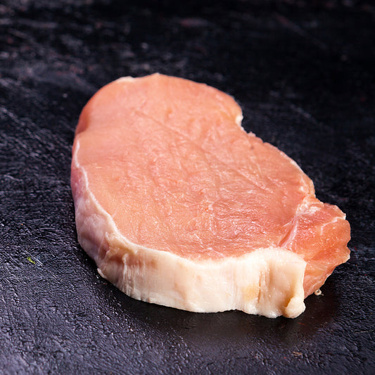 Raw pork chop on a dark surface