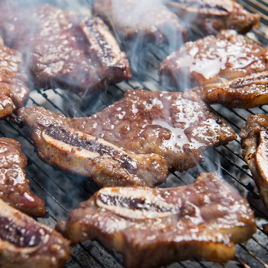 Sizzling marinated beef short ribs grilling on a barbecue, showcasing the juicy and flavorful meat perfect for a Korean BBQ feast