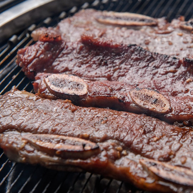 Marinated LA beef short ribs grilling on a barbecue