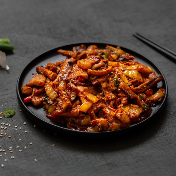 Close-up view of spicy stir-fried squid with vegetables on a dark slate background