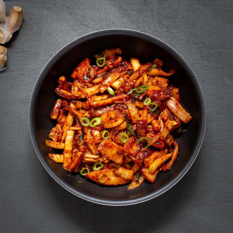 Delicious stir-fried spicy squid topped with green onions served on a black ceramic plate