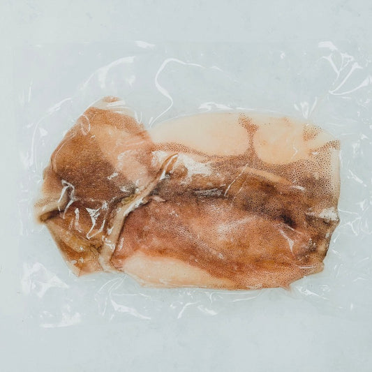 Whole cleaned squid displayed next to its tentacles on a white background