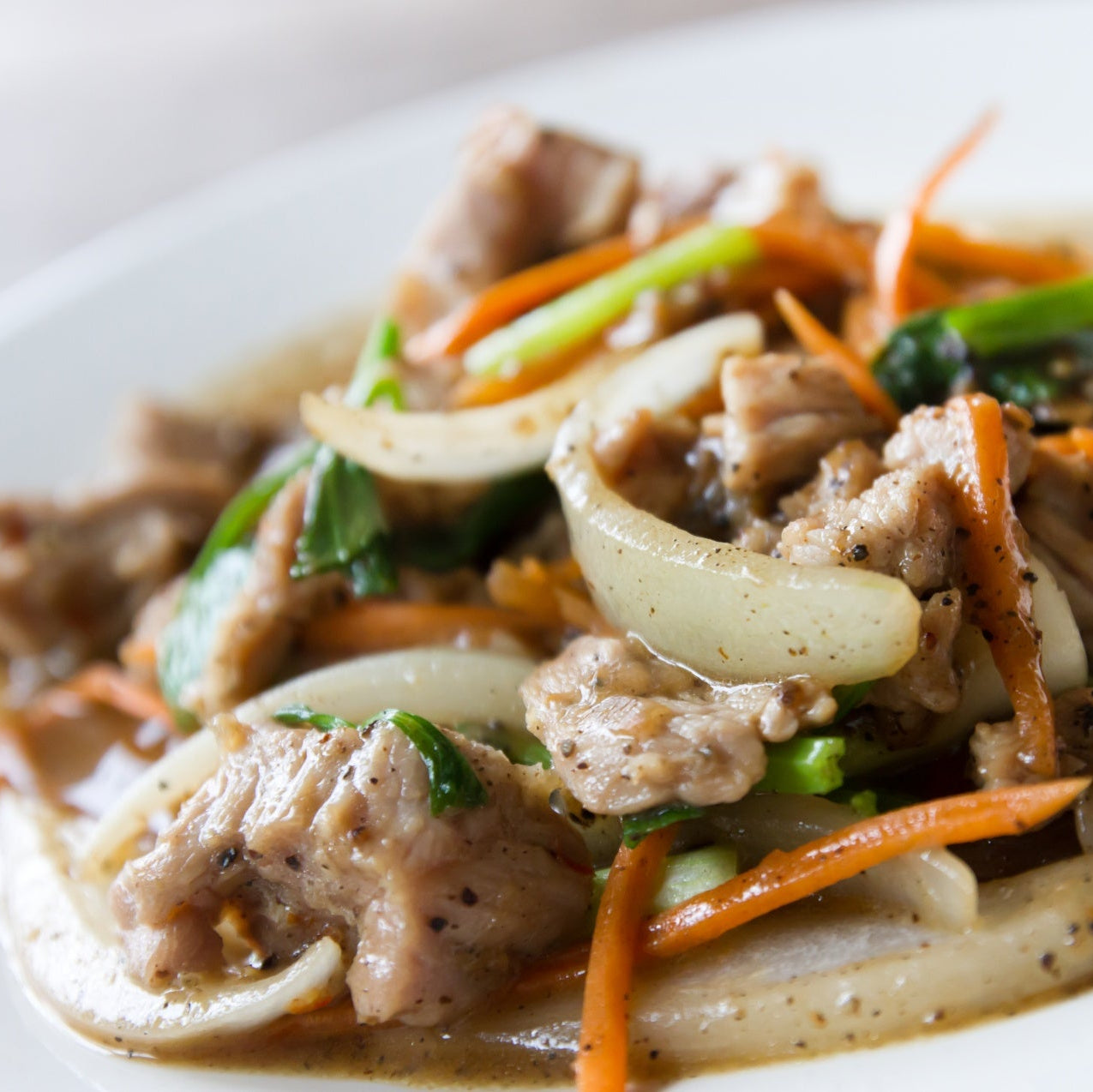 Plated dish of stir-fried meat with vegetables on a white plate