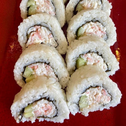  A platter of California rolls made with shredded imitation crab meat, cucumber, and avocado, wrapped in rice and seaweed. The sushi rolls are neatly arranged on a red plate, showcasing the creamy texture and pinkish-white color of the imitation crab filling