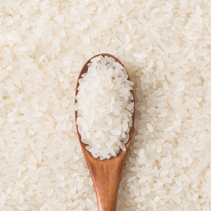 Close-up of milled short grain rice with a wooden spoon filled with rice grains