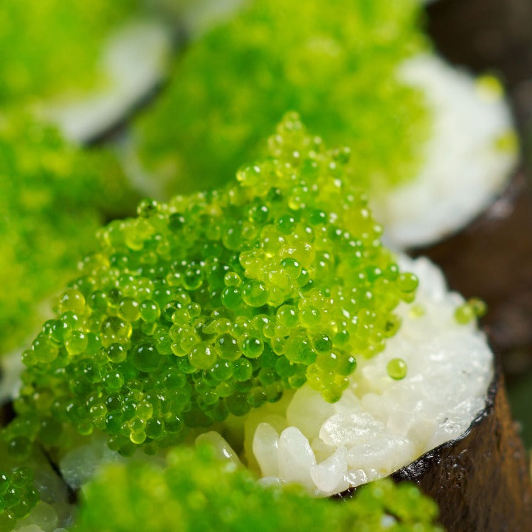 Jalapeno Capelin Roe garnished on a sushi roll, highlighting the bright green roe against the white rice and seaweed