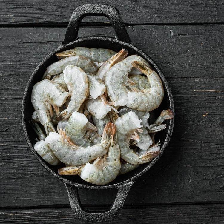 Frozen white shrimp in a black cast iron pot, ready for cooking
