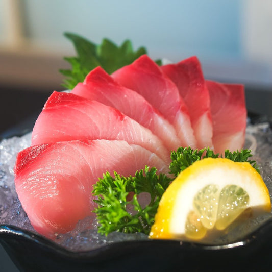 Fresh yellowtail sashimi served on a bed of ice with garnishes of parsley and a lemon wedge. Ideal for a gourmet seafood presentation in sushi bars and fine dining